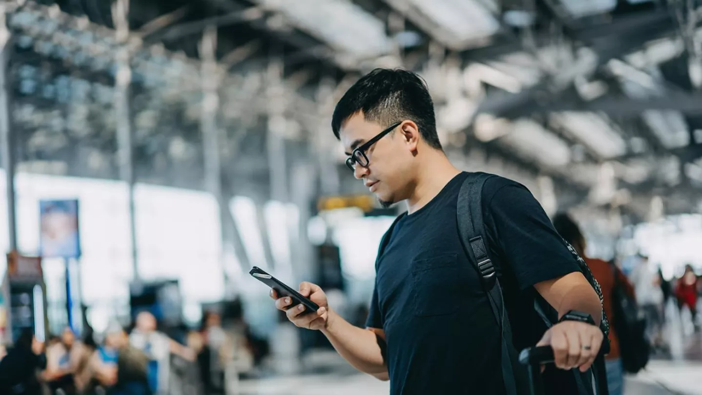 A man checks his phone at a train station