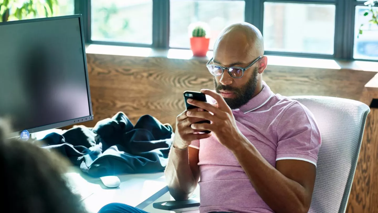 A man uses his smartsphone to research a short codes program