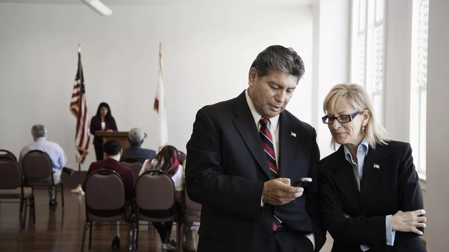 Two people in a courtroom check a phone