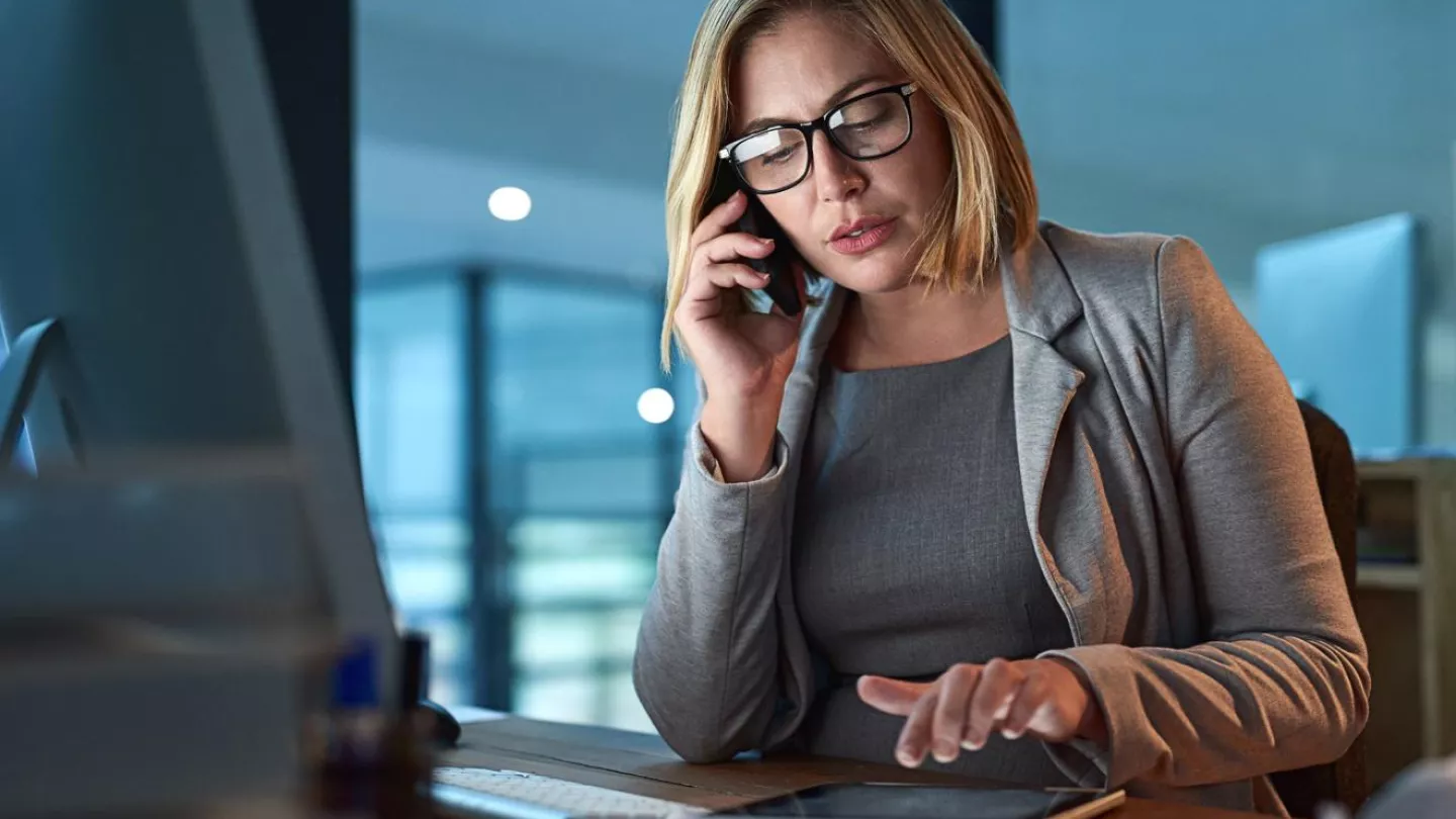 Image of woman on phone typing on a computer