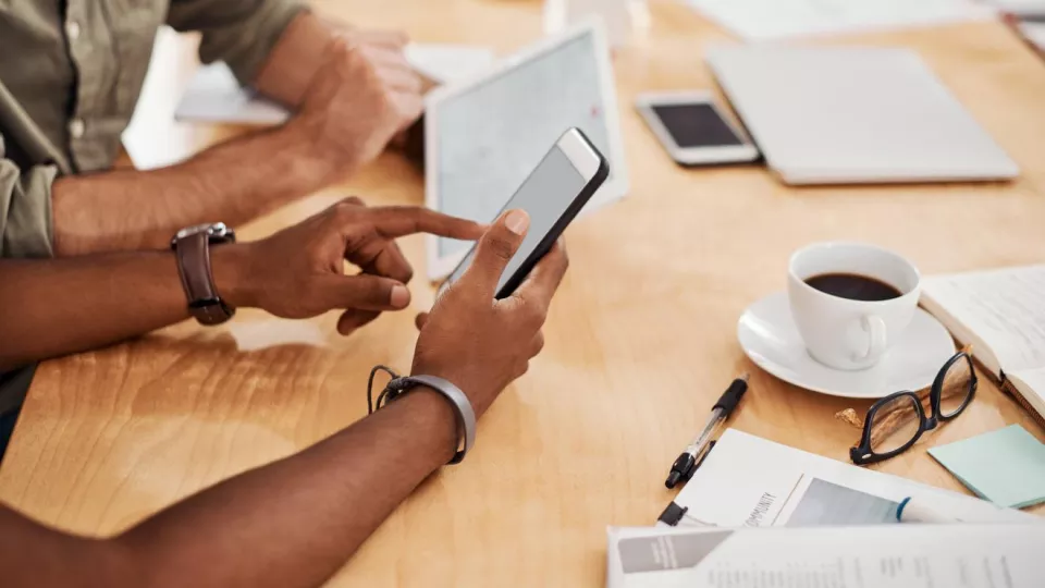 A closeup photo of two men using a mobile phone to apply for short codes