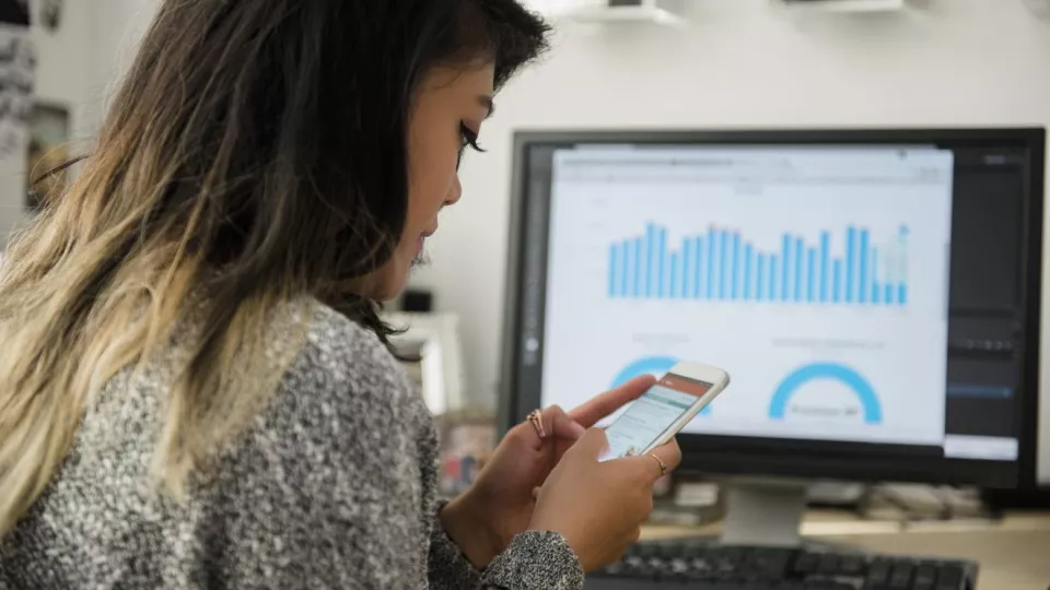 Woman uses her mobile phone while looking at stats